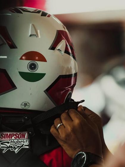 A mechanic helps a driver with his helmet.