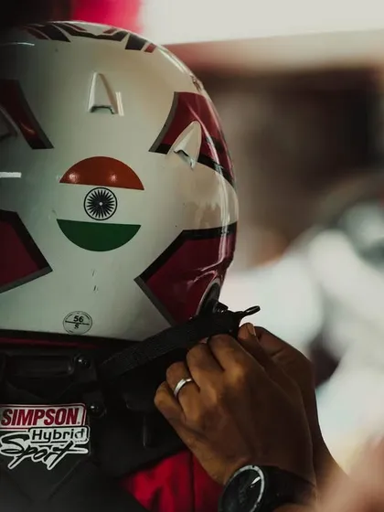 A mechanic helps a driver with his helmet.