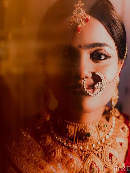 A powerful and artistic bridal portrait with a slow shutter effect. The bride's intense gaze and traditional jewelry, especially the large nath, are the focus of this captivating and moody shot.
