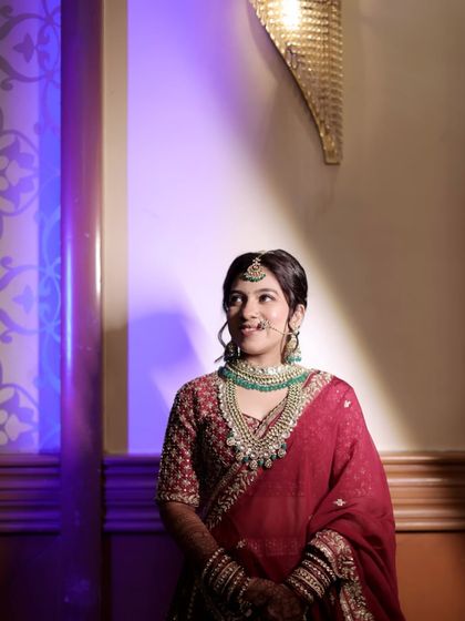 Our bride looks serene and royal in this layered Kundan set with deep green beads, perfectly matching her maroon bridal saree.