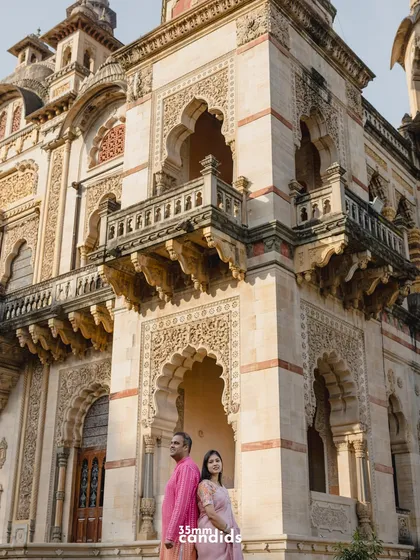 A striking portrait of the couple against the detailed facade of the palace. The composition highlights both the couple and the stunning historical backdrop.