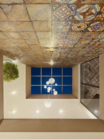 A view from below, looking up at the Terra atrium ceiling. The mosaic tiles, inspired by the land, meet a deep blue skylight, creating a powerful connection between the earth and sky within the home.