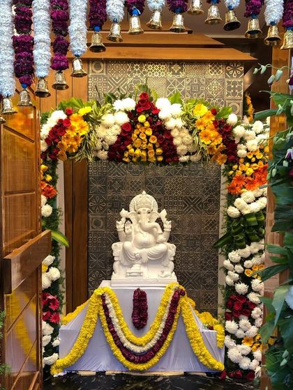 A beautiful moment from the housewarming ceremony at the "Sanman" residence, with the Ganesha idol placed in the elegantly designed pooja room. This space features custom tile work and a traditional bell arrangement.