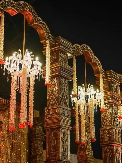 A close-up of the antique carved pillars, adorned with hanging floral chandeliers that combine traditional craftsmanship with elegant lighting.