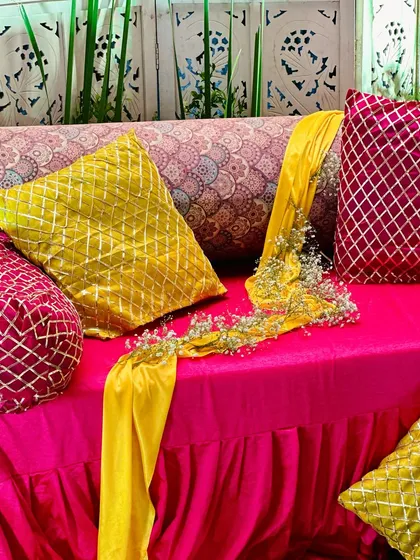 A close-up of the vibrant seating for a Mehendi function, showing the mix of textures and colors in the cushions and fabrics.