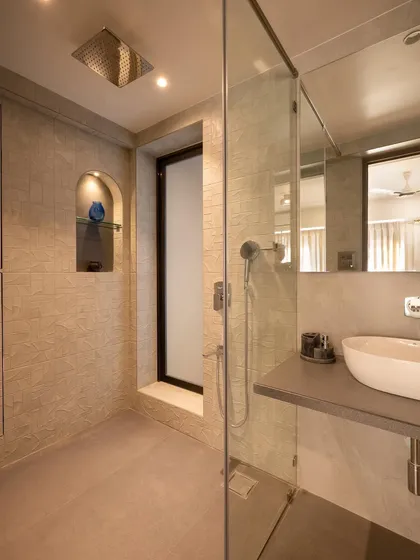 A look inside a modern master bathroom with a spacious walk-in shower. The design uses large format tiles and a floating countertop to create a clean, minimalist feel, with a niche for storing shower essentials.