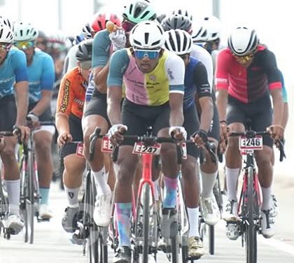The peloton moves as one organism, with riders from different teams sharing the workload at the front. This is a classic scene from the Bangalore Classic Road Race.