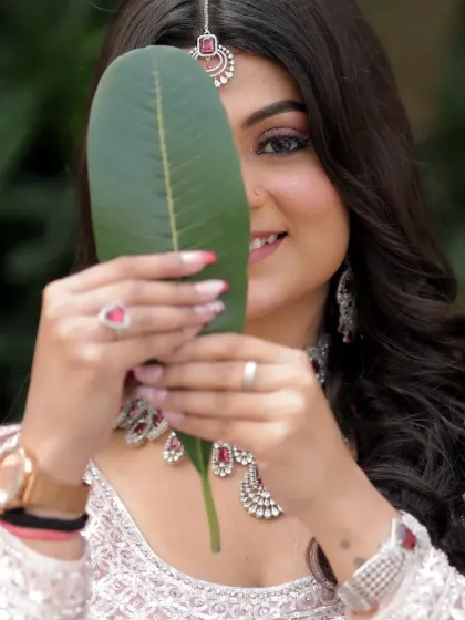 A playful and charming bridal portrait. The bride peeks from behind a large leaf, her smile full of mischief and joy. It’s a unique and creative shot that shows her personality.