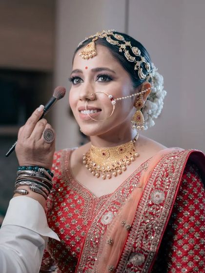 A candid shot of the bride getting her makeup done, capturing her happy smile and the excitement of the getting-ready process.