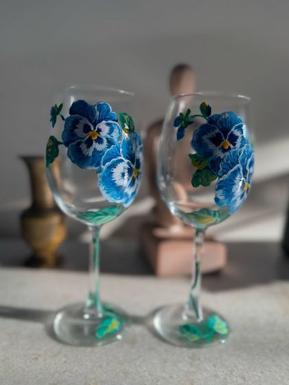 A pair of elegant wine glasses, hand-painted with blue pansies. A beautiful gift for any occasion.