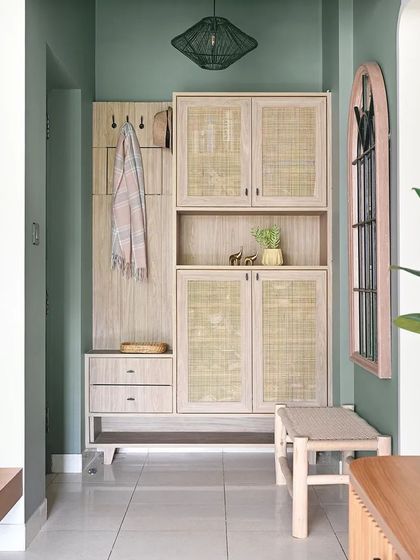 A full view of the custom foyer unit, which includes a bench, shoe storage, cabinets, and a coat niche. The light wood and rattan create a warm and inviting first impression.