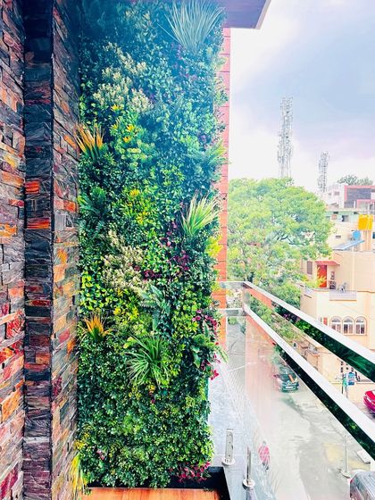 Our green walls pair beautifully with other materials. Here, a lush vertical garden is installed next to a stone-clad wall, creating a rich contrast of natural textures on this modern balcony.