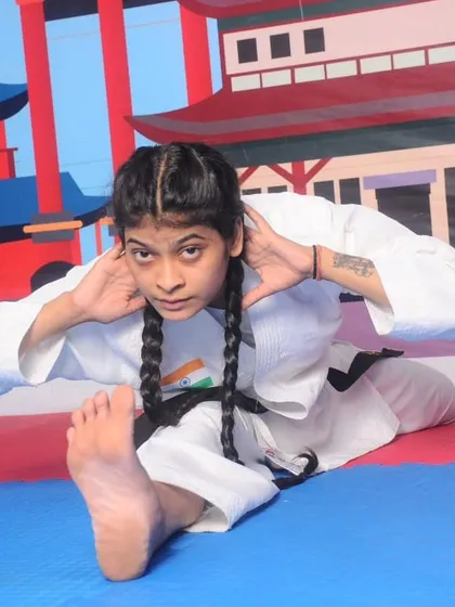 This image shows a student performing a deep stretch, which is essential for developing the flexibility required for advanced karate techniques and injury prevention.