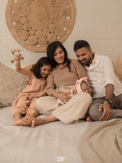 A heartwarming shot of a family of four admiring their newest member, the older sister playing gently with the baby.