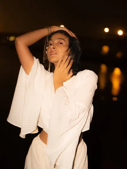 An expressive, hands-on-hair pose. The on-camera flash creates a raw, fashion-magazine style of lighting.