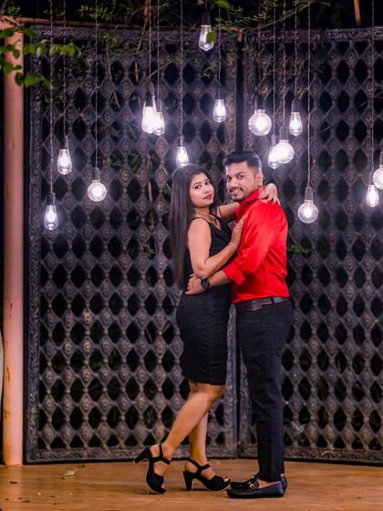 A stylish couple poses against our rustic gate and hanging bulb installation, a popular choice for modern pre-wedding photography.