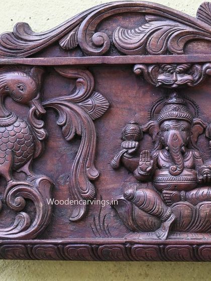 A detail from the 79-inch GajaLakshmi panel, showing Lord Ganesha seated next to a peacock, all carved in a deep wax brown finish.