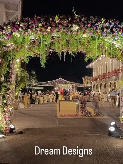 An entrance should feel like stepping into another world. This lavish floral arch, overflowing with purple and pink blooms and interwoven with greenery and lights, provides a spectacular welcome to an evening of celebration.