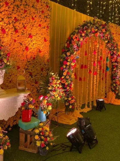A stunning Haldi stage with a wall of marigolds and a floral arch, creating a rich and festive backdrop for photos.