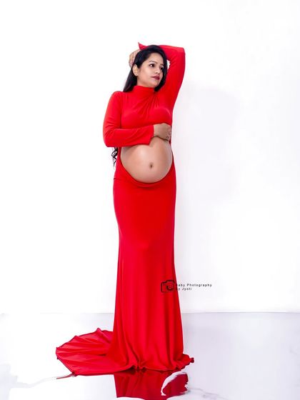 A bold and modern maternity pose in a red cutout gown, showcasing the baby bump. This is for the mom-to-be who wants a confident and stylish portrait.