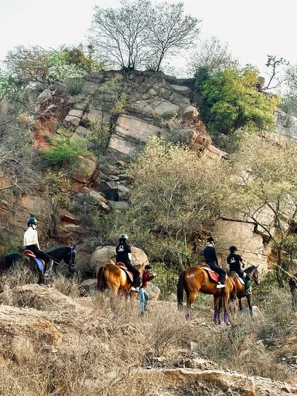 Our riders navigate a path along the base of a beautiful rock formation. The natural beauty of the Aravalis is the true star of our horseback safaris.