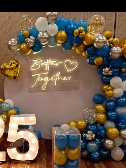 A 'Better Together' theme for a 25th anniversary. This setup features a blue, gold, and white balloon arch, a custom neon sign, and large light-up numbers.