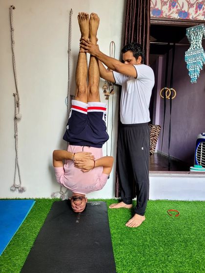 A still image of the hands-free headstand with support. This shows the trust between teacher and student.