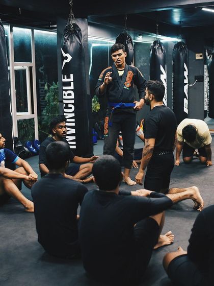 I lead a discussion with a group of students sitting on the mat, explaining a concept or technique.