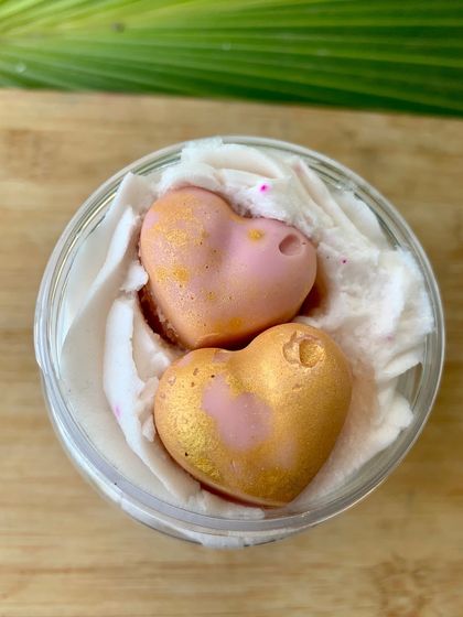 Comfort in a jar. This is my Warm Vanilla whipped soap, topped with two adorable pink and gold heart-shaped mini soaps. It's a sweet, cozy scent that feels like a hug.