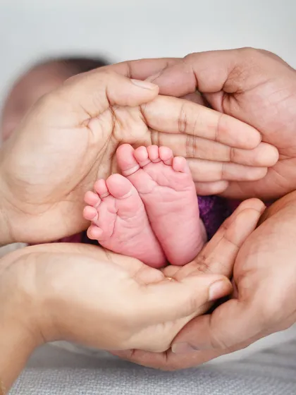 A baby's feet cradled in the hands of their parents. It's a classic and powerful image symbolizing the family's love and support.