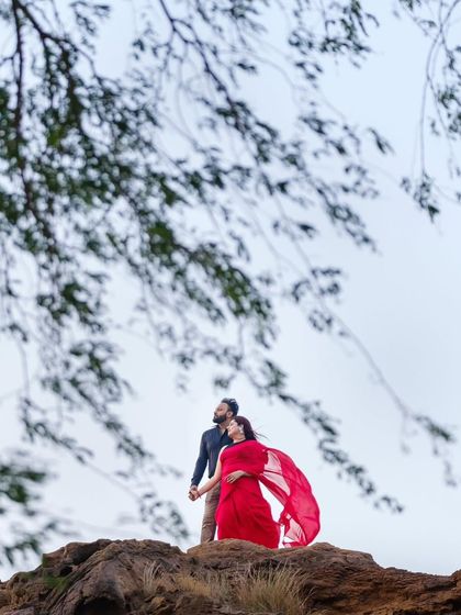 A beautiful, romantic shot of the couple on a rocky hill in Jaisalmer. Her red saree stands out beautifully against the sky and the foliage.