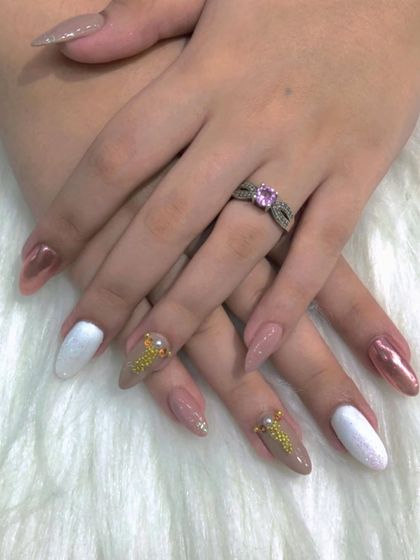 A creative mix of nude, white, and rose gold chrome nails with gold stud accents.