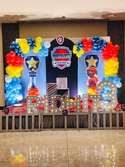 A Paw Patrol themed birthday party, complete with the iconic shield logo, character cutouts, and a red, blue, and yellow balloon arch.
