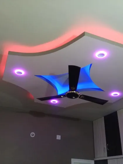 For this bedroom, we installed a dynamic false ceiling with multi-color LED lighting options. The design allows the client to change the room's ambiance with remote-controlled red, blue, and purple lights, highlighting the curved and layered structure.