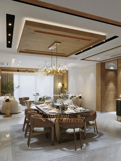 An open-plan living and dining area where a wooden false ceiling and a grand chandelier define the dining space, creating a warm and luxurious feel.