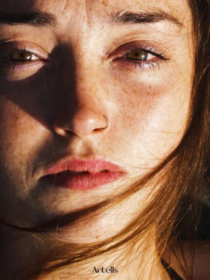 An intense, sun-drenched close-up from the "To the waters" editorial in Artells magazine, showing the raw texture of skin and freckles.