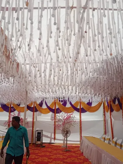 This is the interior of a large mandap I set up for an event. The ceiling is decorated with hanging white paper ribbons, while the sides feature traditional yellow and purple drapes over the seating area.