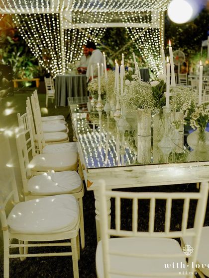 A long view of the mirrored dining tables reflecting the canopy of lights. This setup creates a stunning visual effect, making the dining experience feel incredibly special and immersive.