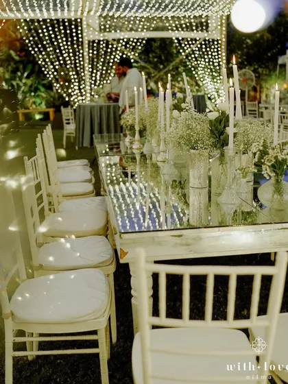 A long view of the mirrored dining tables reflecting the canopy of lights. This setup creates a stunning visual effect, making the dining experience feel incredibly special and immersive.