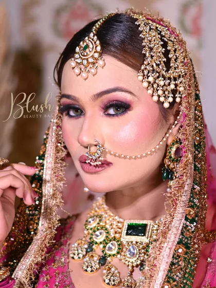 This close-up highlights the sharp, defined eye makeup and the flawless base. The use of a passapatti and heavy nose ring are key elements of this traditional Nikaah bridal look.