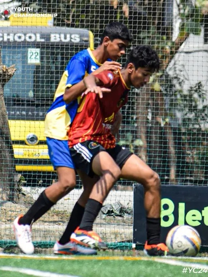 A player shields the ball from an opponent, demonstrating strength and ball control.