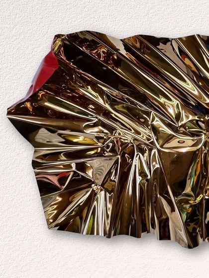 The crumpled texture of this gold-toned stainless steel sculpture creates an infinite number of reflections.