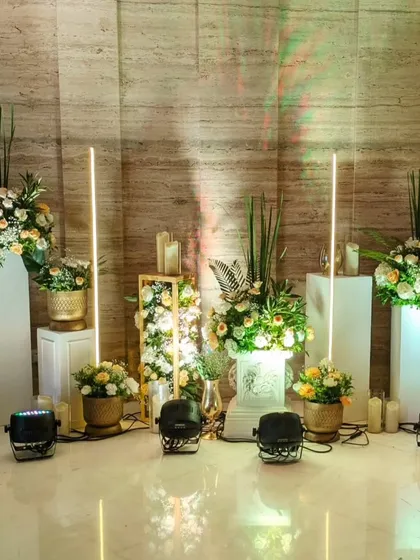 This modern decor corner features floral arrangements on illuminated pedestals, accented by tall, glowing light sticks for a chic and contemporary feel.