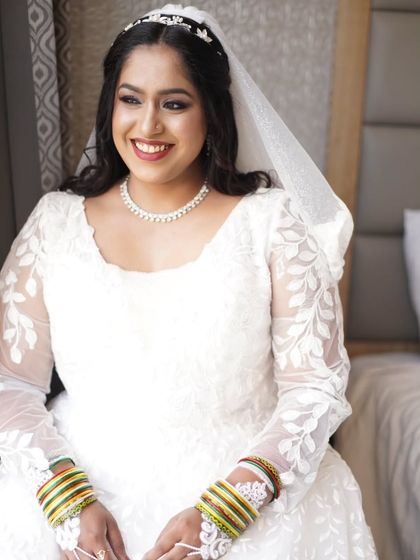 A smiling portrait of the bride in her beautiful white gown. The makeup is designed to make her feel timeless and elegant on her special day.