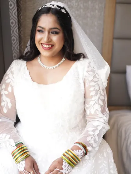 A smiling portrait of the bride in her beautiful white gown. The makeup is designed to make her feel timeless and elegant on her special day.