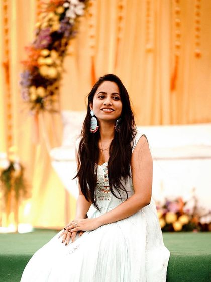 A portrait from a Mehendi event we decorated. The setup included a floral arch with a mix of purple, yellow, and white flowers against a soft yellow curtain.