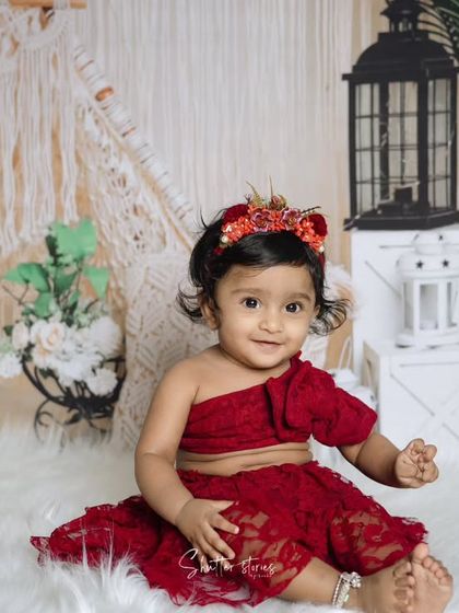 A beautiful portrait of a one-year-old girl in a red lace outfit, ready to celebrate her first birthday.