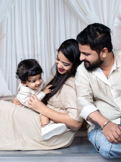 A relaxed and candid photo of a family of three sitting together on the floor, sharing a natural interaction.