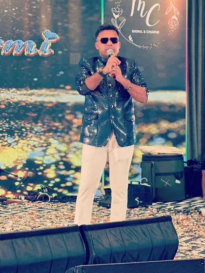 Holding the mic, ready to engage the crowd. The shimmering jacket catches the stage lights beautifully, adding to the overall spectacle of the event.
