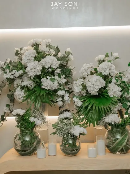 A clean and modern floral arrangement of white hydrangeas and greenery in clear glass vases, creating a fresh and elegant look.